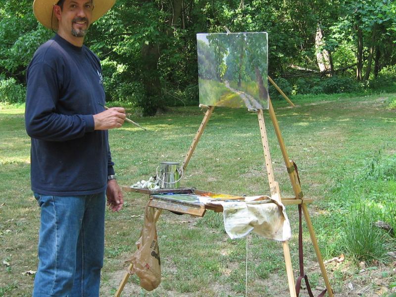 Armand Cabrera painting an oil painting, using his Take It Easel en plein air. The Take it easel supports her artwork and all her art supplies.